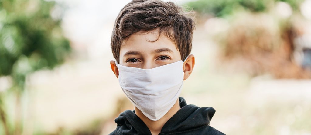 Portrait of 10 year old boy wearing homemade protective mask sunning during quarantine. Coronavirus, Covid-19 and pandemic concept